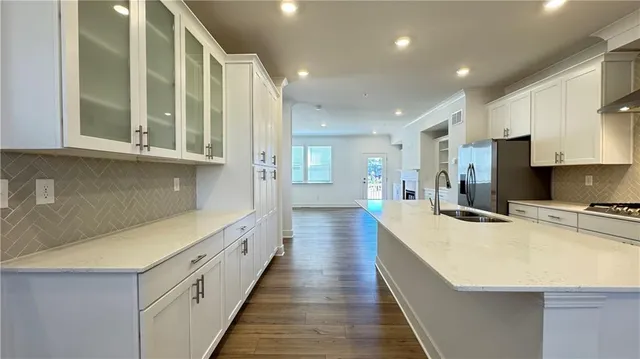 a kitchen with white cabinets and wooden floor