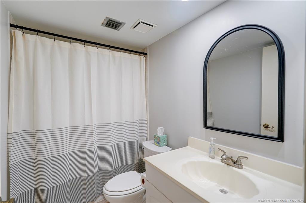 5539 Northeast Gulfstream Way Stuart, FL 34996 - Photo 22 of 26 a bathroom with a sink a toilet and shower curtain