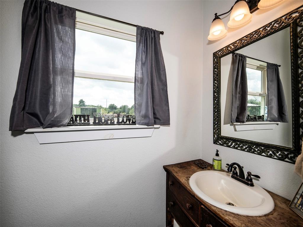 4983 Applegate Road Bowie, TX 76230 - Photo 17 of 40 a bathroom with a sink a mirror and a window