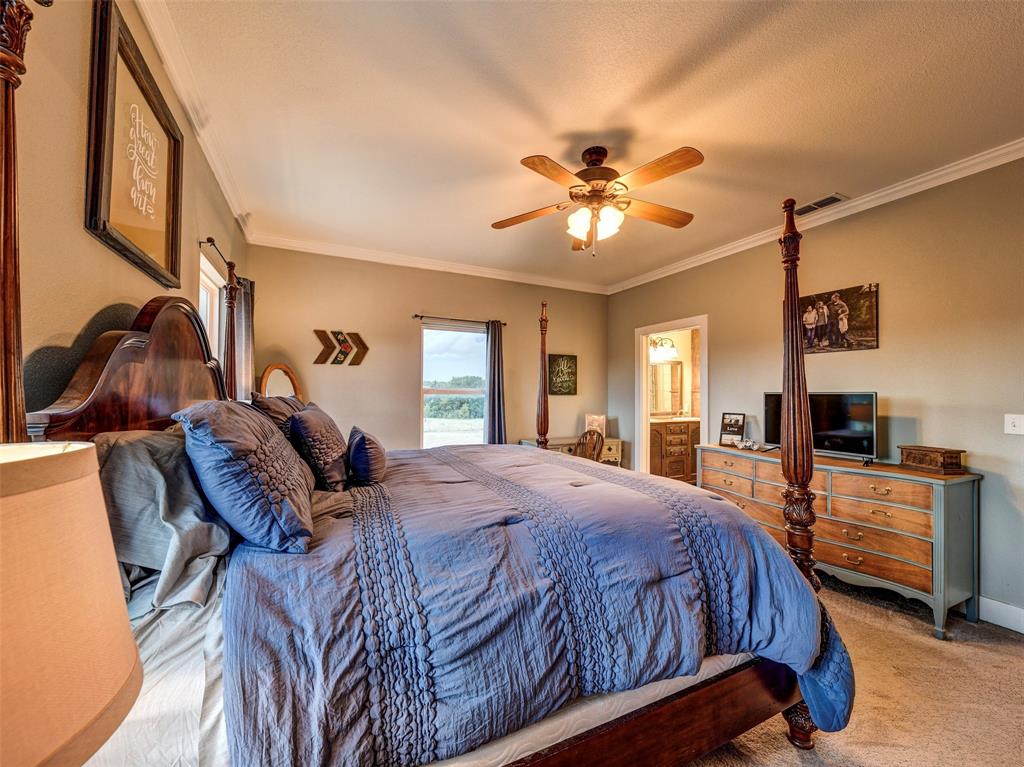 4983 Applegate Road Bowie, TX 76230 - Photo 19 of 40 a bedroom with a bed a ceiling fan and a flat tv screen