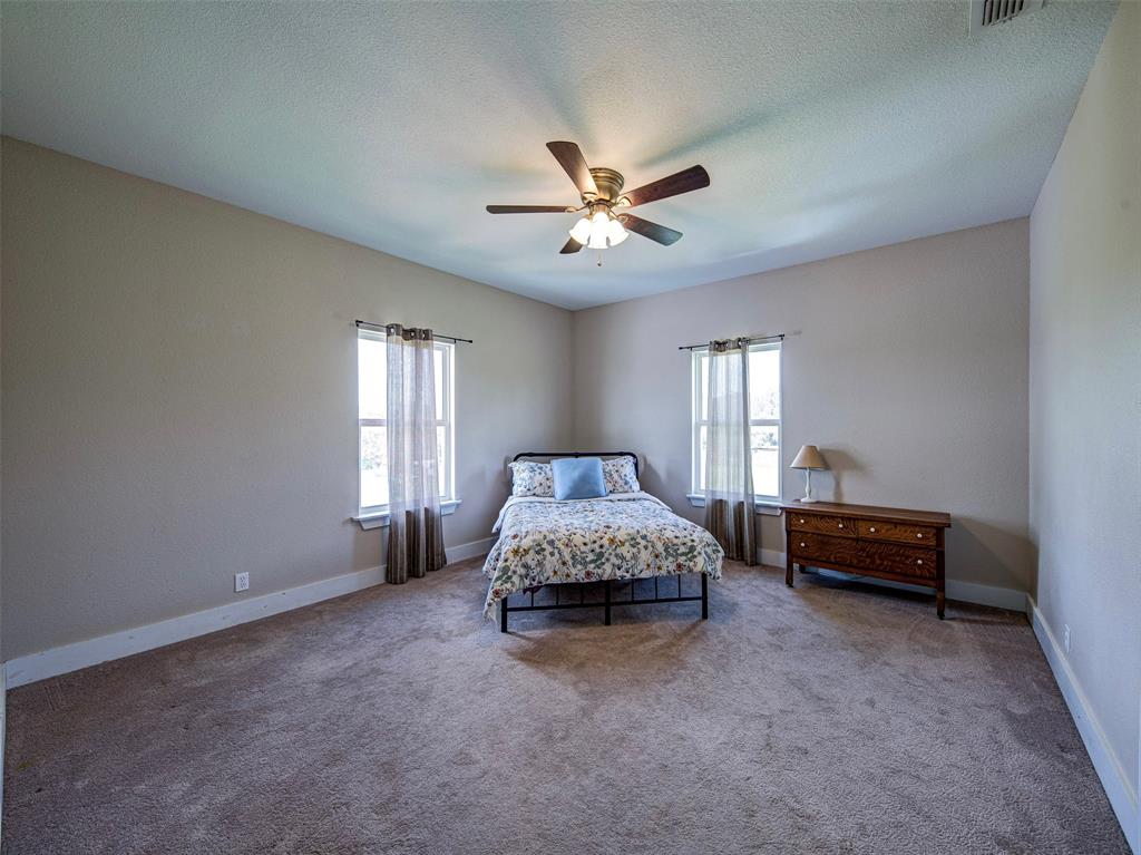 4983 Applegate Road Bowie, TX 76230 - Photo 26 of 40 a spacious bedroom with a bed and a chandelier