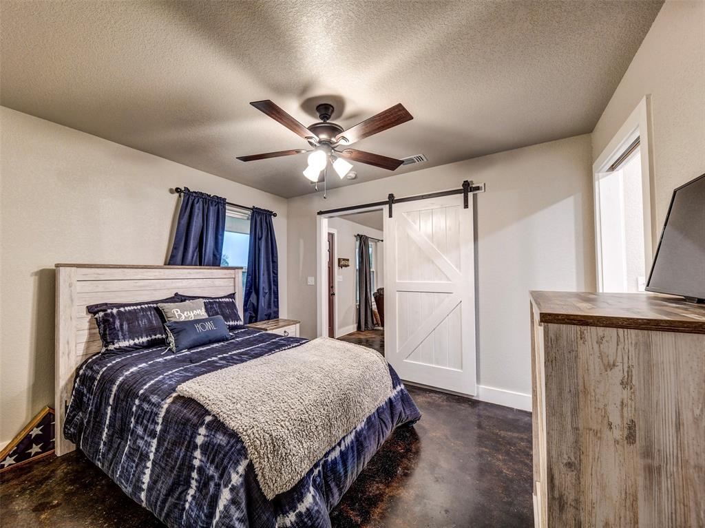 4983 Applegate Road Bowie, TX 76230 - Photo 33 of 40 a bedroom with a large bed and a chandelier