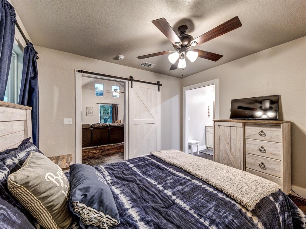 4983 Applegate Road Bowie, TX 76230 - Photo 34 of 40 a bedroom with a bed and a flat tv screen on dresser