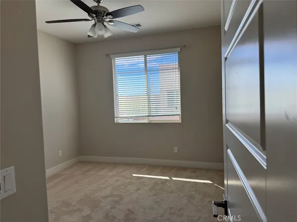 an empty room with windows and fan