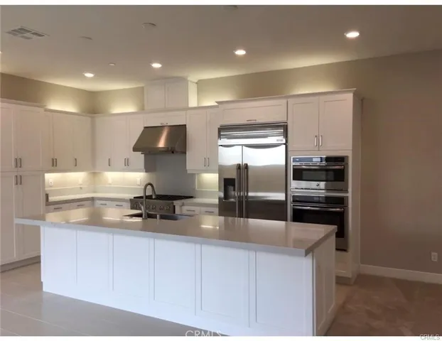 a kitchen with kitchen island a counter top space cabinets and stainless steel appliances