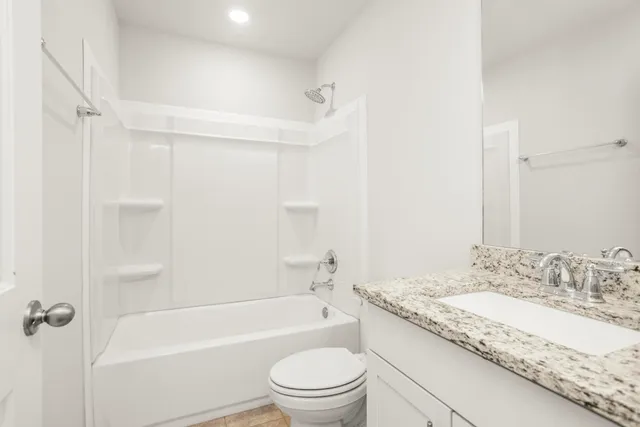 a bathroom with a granite countertop sink a toilet and shower