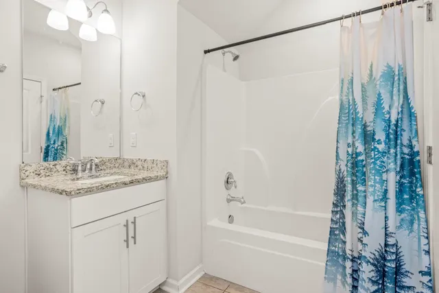 a bathroom with a granite countertop sink a mirror a vanity and a shower