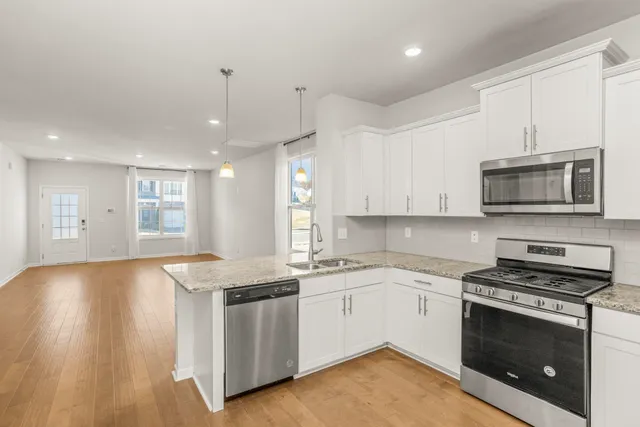 a kitchen with stainless steel appliances granite countertop a stove a sink and a microwave