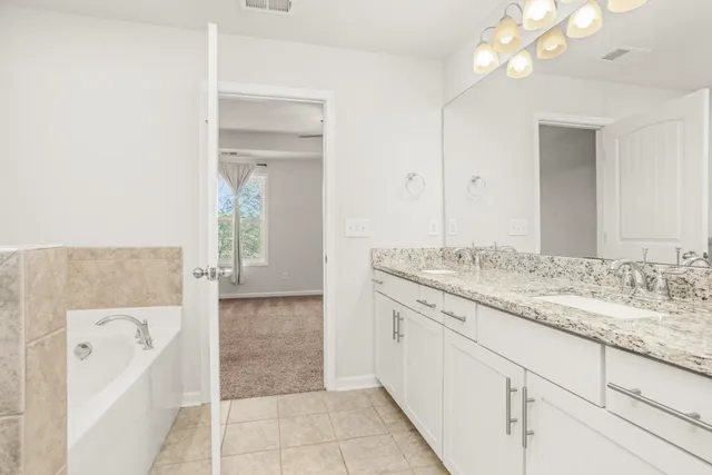 a bathroom with a granite countertop sink and a bathtub