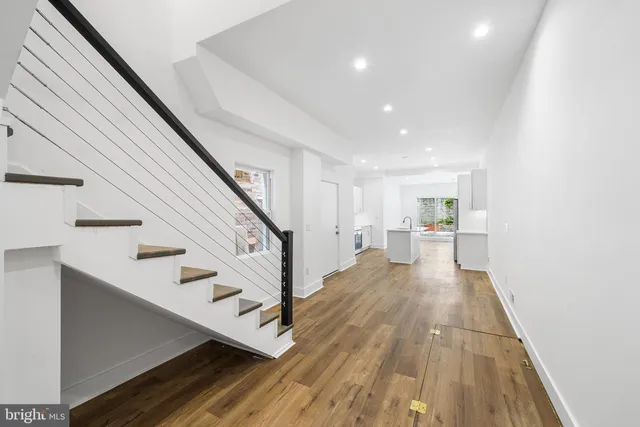 a kitchen with granite countertop a refrigerator oven a sink dishwasher and white cabinets with wooden floor