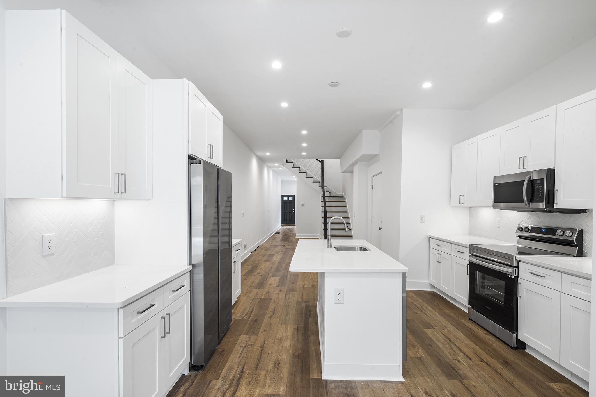 952 North 5th Street Philadelphia, PA 19123 - Photo 40 of 49 a large kitchen with stainless steel appliances kitchen island granite countertop a stove a sink a refrigerator and a white cabinets with wooden floor