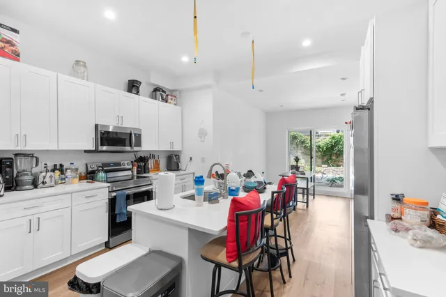 a kitchen with stainless steel appliances kitchen island granite countertop a table chairs sink and cabinets