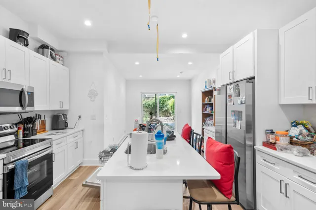 a kitchen with stainless steel appliances a dining table chairs sink refrigerator and microwave