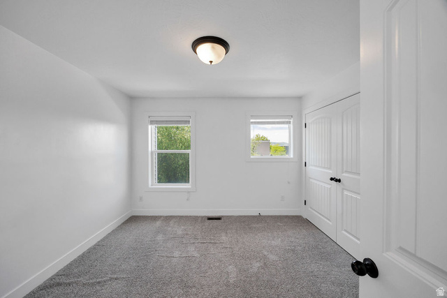 2483 South 1296th Street West Logan, UT 84321 - Photo 14 of 45 Bright interior space with white walls, gray carpeting, a flush-mount ceiling light fixture, and two windows