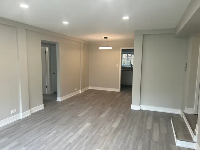an empty room with wooden floor and entrance