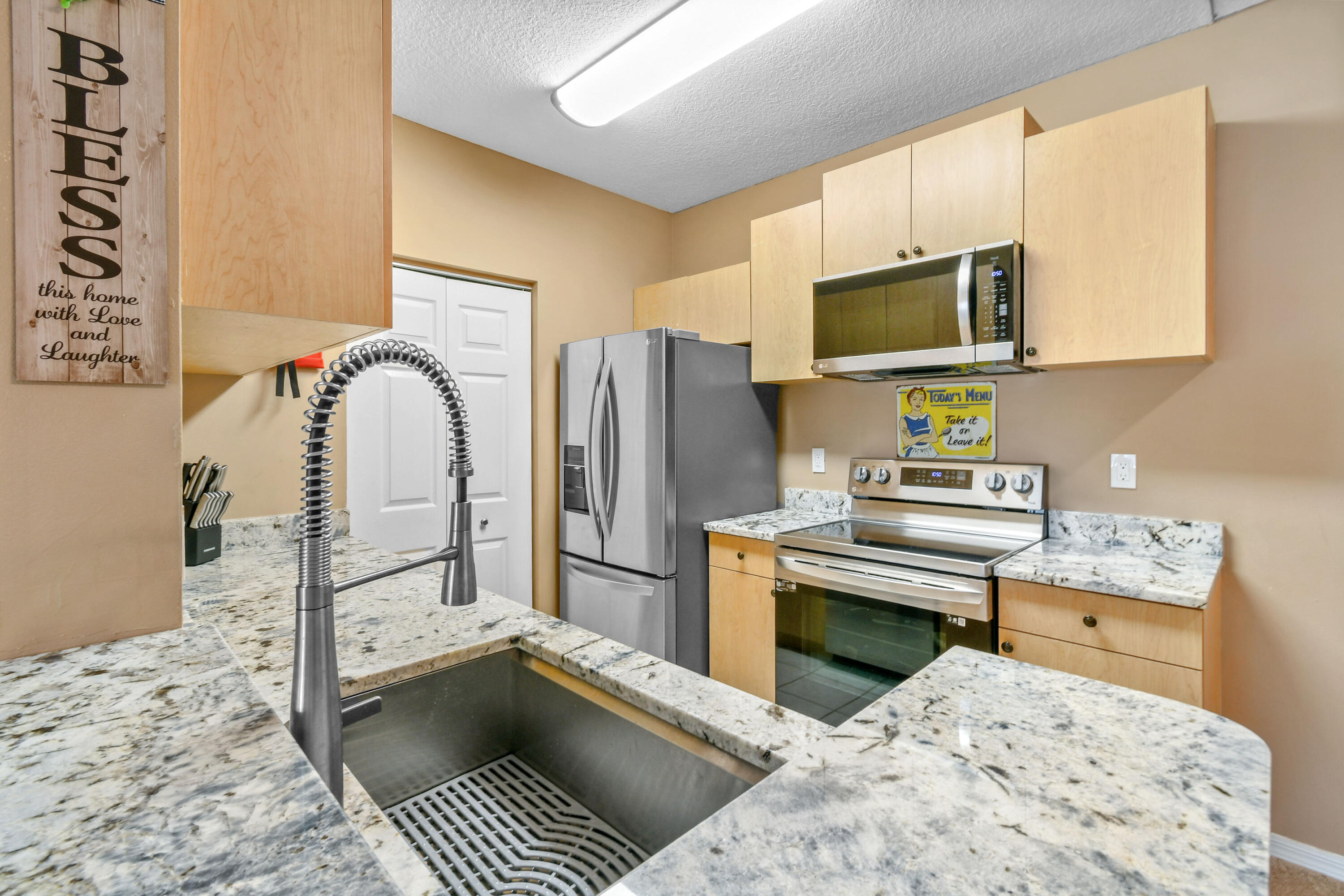 10354 Fox Trail Road South, Unit 1505 West Palm Beach, FL 33411 - Photo 12 of 76 a kitchen with stainless steel appliances kitchen island granite countertop a refrigerator and a stove top oven