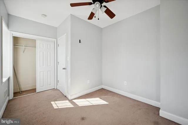 an empty room with a ceiling fan and carpet