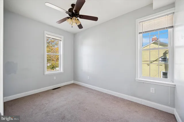 an empty room with windows and fan