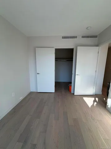 a view of an empty room with wooden floor and closet