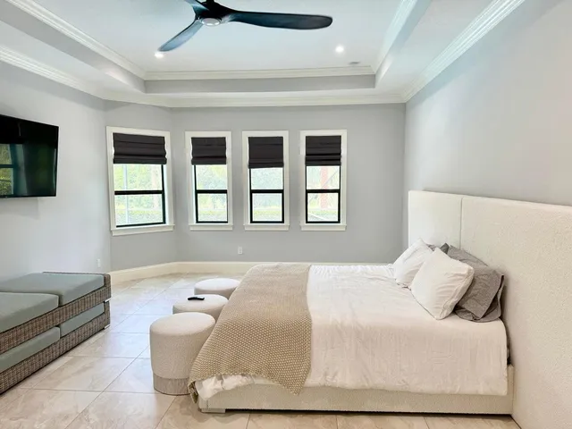 a bedroom with a bed a flat screen tv and a window