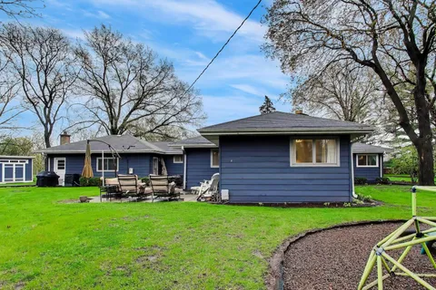 a front view of a house with a garden and trees