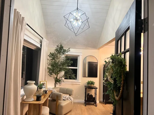 a living room with furniture a large window and a chandelier