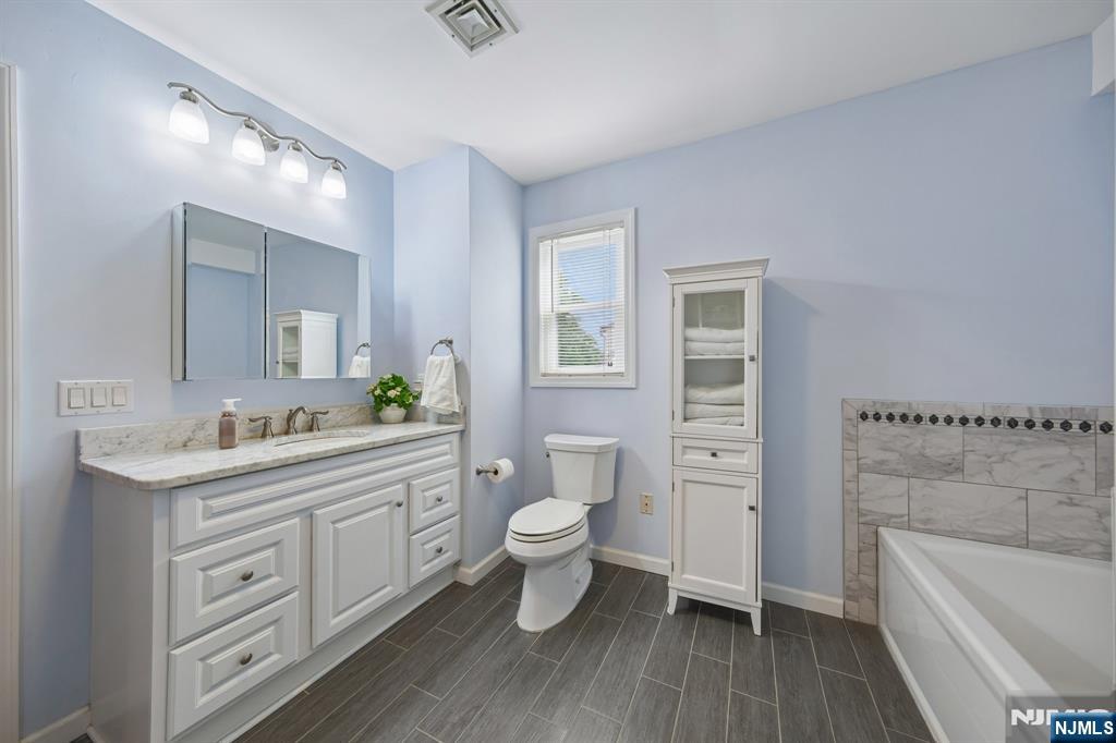 562 Valley Road Clifton, NJ 07013 - Photo 28 of 35 a bathroom with a granite countertop toilet a sink and a bathtub