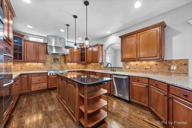 a kitchen with stainless steel appliances granite countertop a sink a stove and a wooden floors