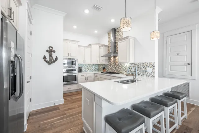 a kitchen with stainless steel appliances kitchen island granite countertop a table chairs and a refrigerator