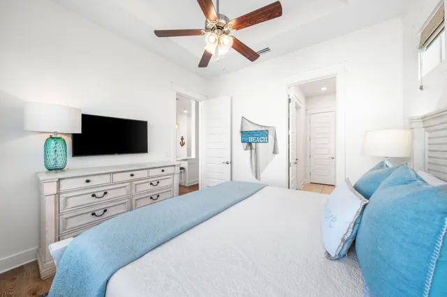 a bedroom with a bed a flat screen tv on dresser and a chandelier