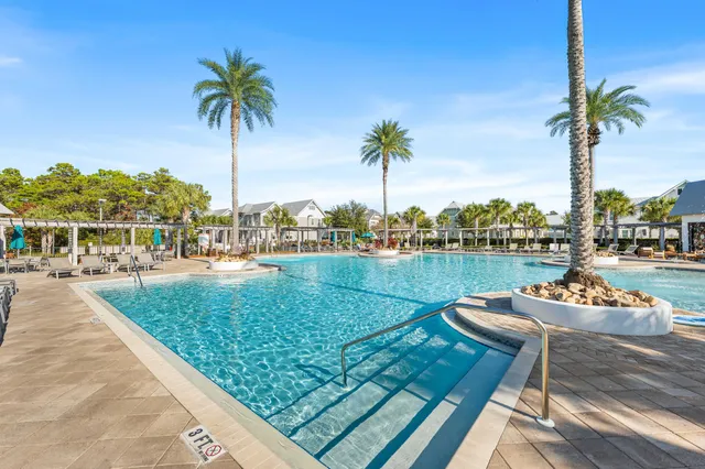 a view of a lake with couches and palm trees