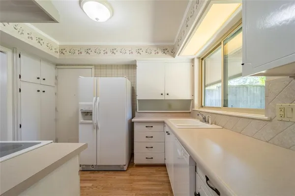 a kitchen with a sink a stove cabinets and wooden floor