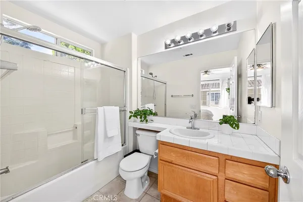 a bathroom with a granite countertop sink a toilet a mirror and shower