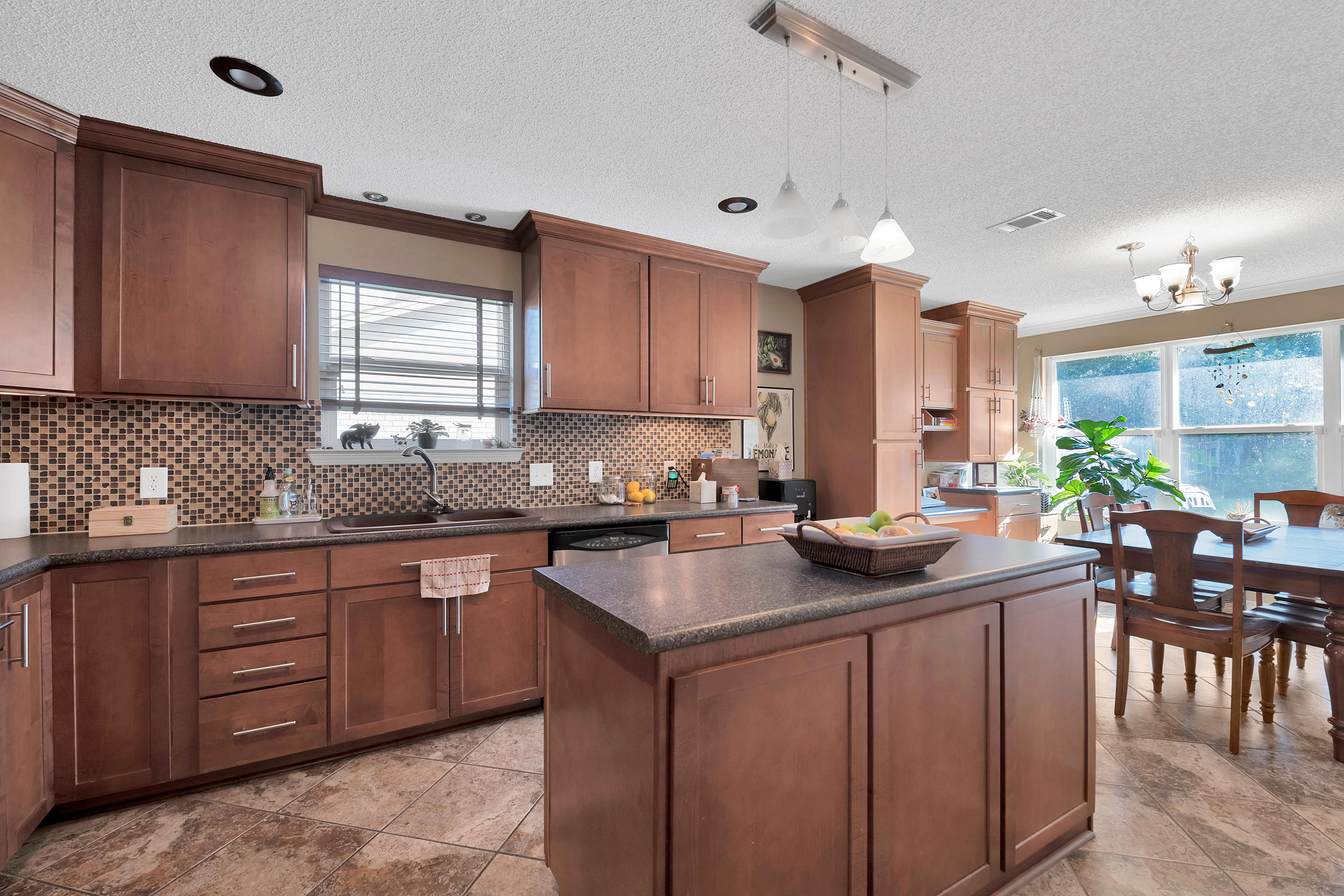 2734 Augustus Road Navarre, FL 32566 - Photo 16 of 23 a kitchen with stainless steel appliances granite countertop wooden cabinets a sink a stove a dining table and chairs
