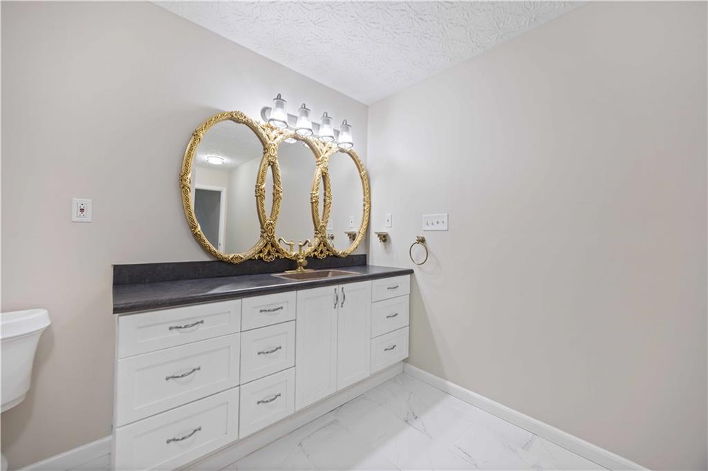 25 Gas Line Road Phenix City, AL 36870 - Photo 28 of 52 Bathroom featuring marble look tiles, vanity, and a textured ceiling