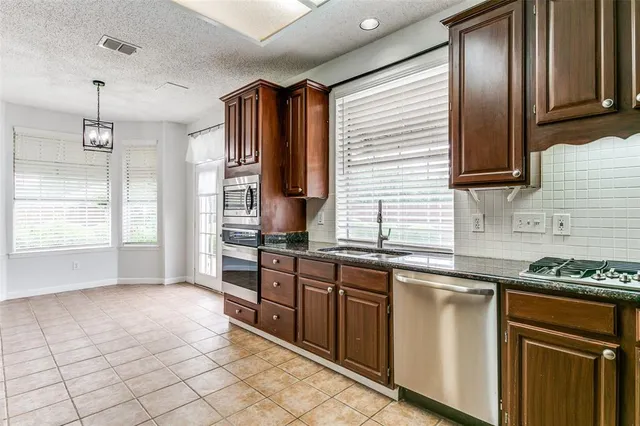 a kitchen with stainless steel appliances granite countertop a sink and a refrigerator