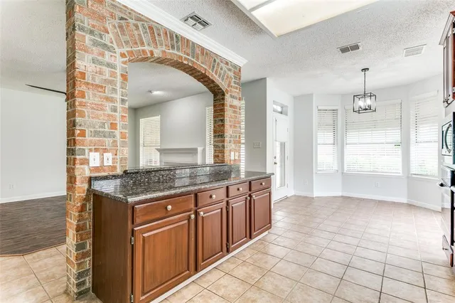 a hall with kitchen island granite countertop a sink and a stove
