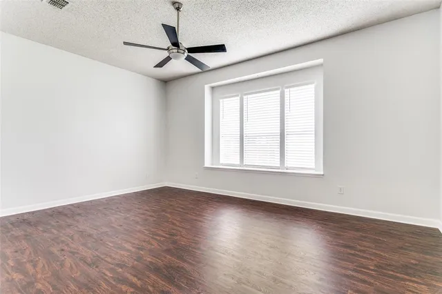 a view of a livingroom with wooden floor a ceiling fan and windows