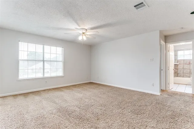 an empty room with chandelier fan and windows