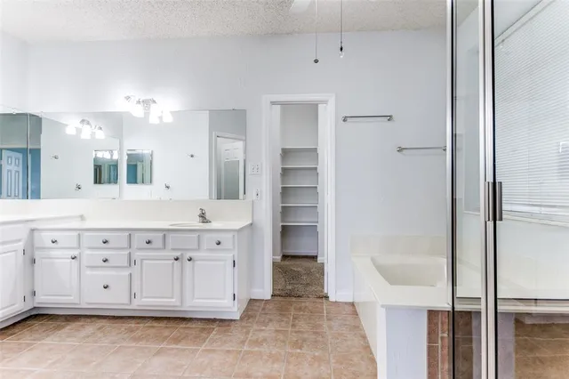 a spacious bathroom with a granite countertop sink a mirror a bathtub and a shower