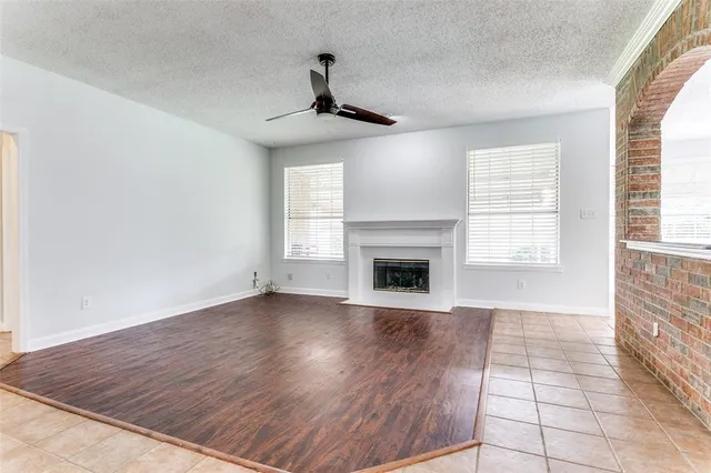 an empty room with wooden floor fireplace and windows