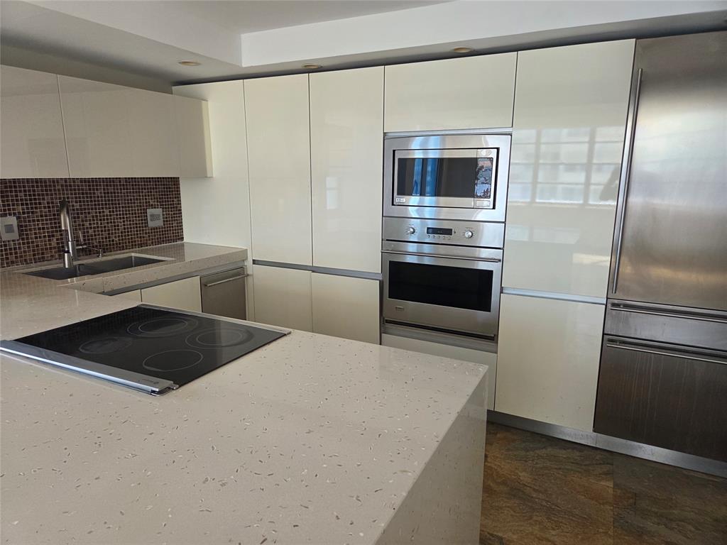 2750 Northeast 183rd Street, Unit 1803 Aventura, FL 33160 - Photo 5 of 14 a kitchen with kitchen island a counter top space wooden floor and stainless steel appliances