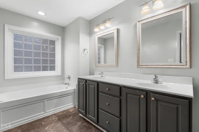 a bathroom with a double vanity sink mirror and bathtub