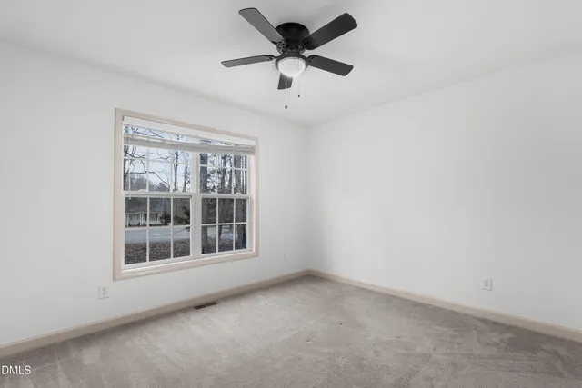 an empty room with a window and a ceiling fan