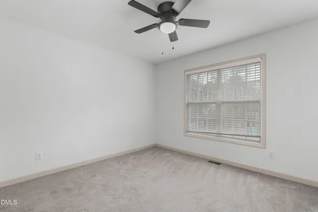 an empty room with a window and a fan