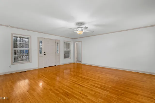 a view of an empty room with window and chandelier fan
