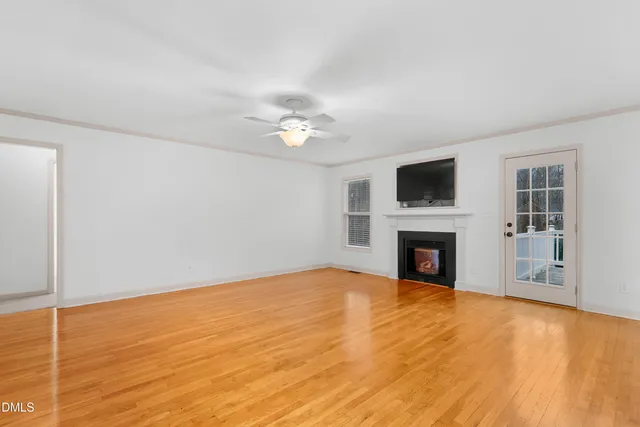 a view of empty room with fireplace and wooden floor