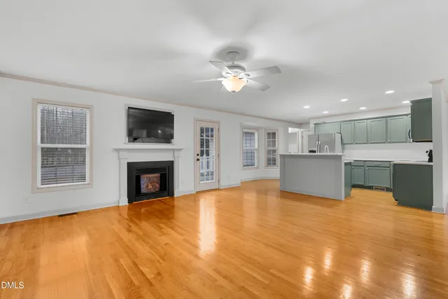 a view of a livingroom with a fireplace a ceiling fan and windows
