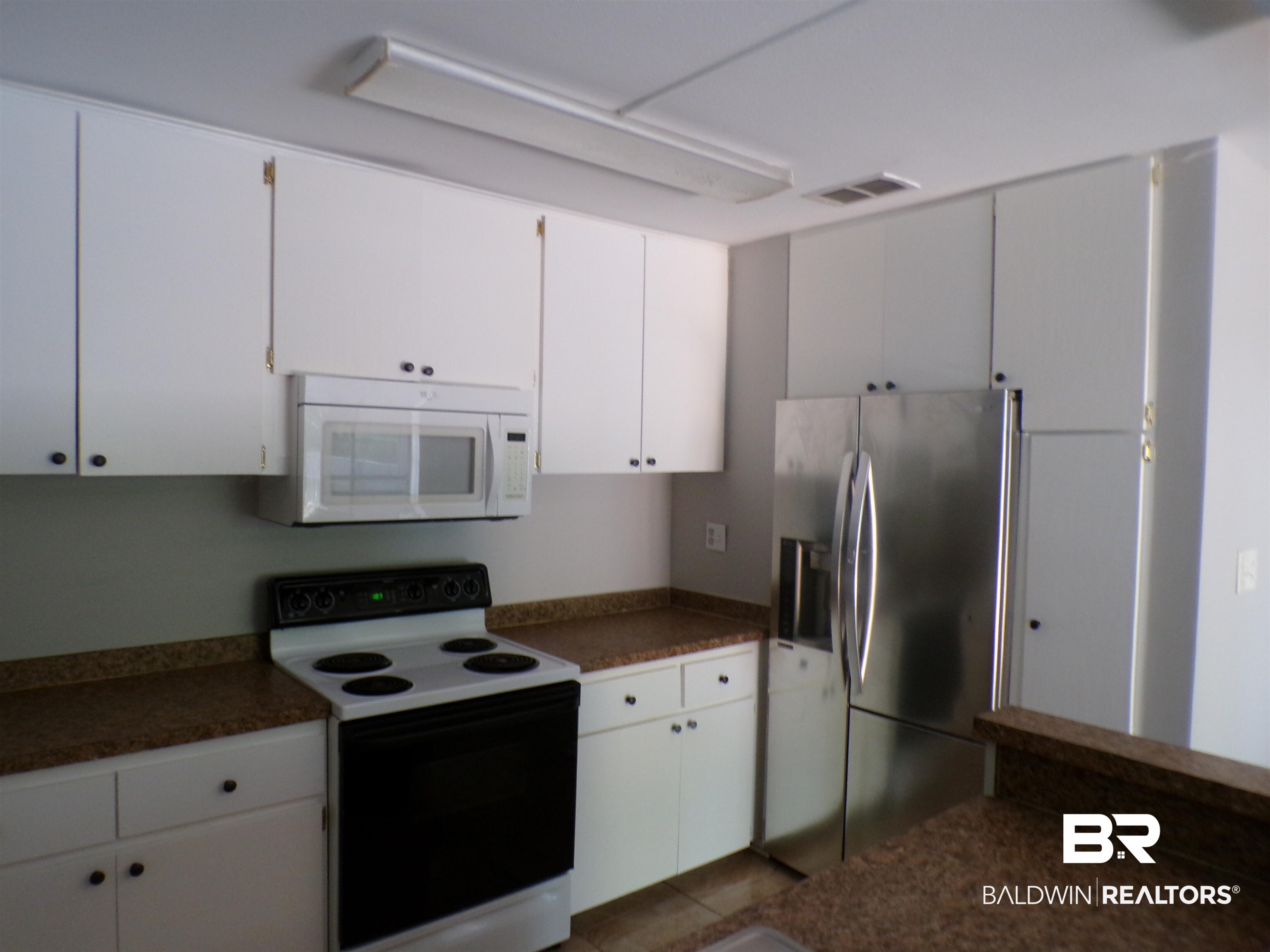 1152 North Alston Street, Unit 1152 Foley, AL 36535 - Photo 8 of 16 Kitchen featuring white cabinetry, brown textured countertops, a built-in microwave, an electric range, and a stainless steel refrigerator