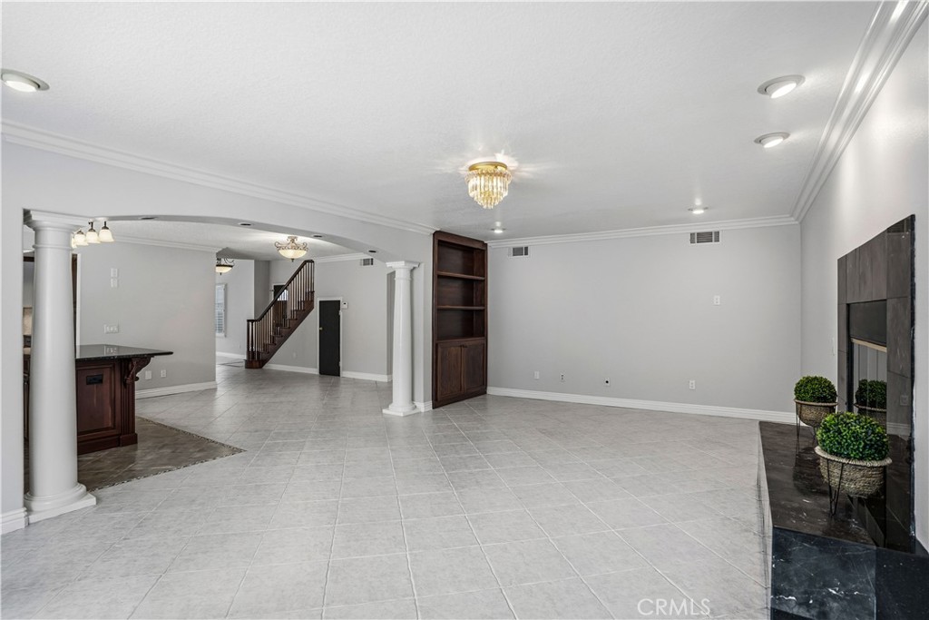 6568 Balzac Circle Riverside, CA 92506 - Photo 17 of 62 Family room was made to match the outside with roman pillar colums for a dramitic entry into the gas fireplace room. Fireplace is granite trimmed room. Custom wood bookcases on both sides of the roamn colums! Custom chandelier with recessed lighting. All tiled. Crown molding above and below.
